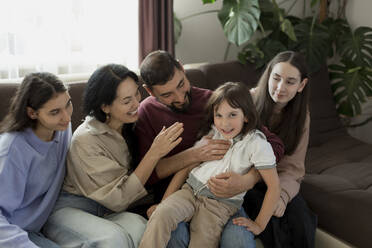 Happy family sitting on sofa at home - LLUF00421