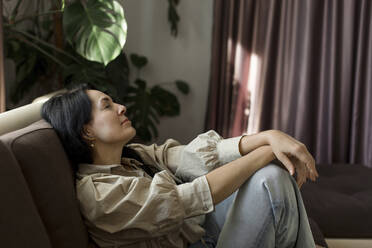 Woman resting on sofa at home - LLUF00427