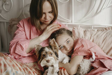 Mutter und Tochter entspannen sich mit Hund auf dem Bett zu Hause - SEAF00155