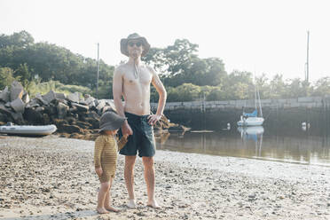 Mann ohne Hemd steht mit Sohn am Strand im Urlaub auf Sand - ACTF00160