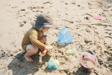 Junge mit Sonnenhut spielt im Sand am Strand - ACTF00165