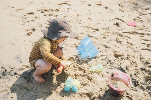 Junge mit Sonnenhut spielt im Sand am Strand - ACTF00165