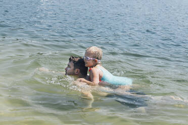 Mann mit Tochter auf dem Rücken schwimmt im Meer - ACTF00168