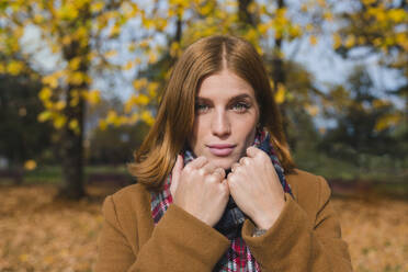 Beautiful young woman wearing scarf in autumn park - MGIF01153