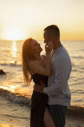 Romantisches junges Paar genießt den Sonnenuntergang am Strand - SSGF00335