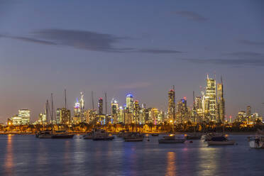 Australien, Victoria, Melbourne, Yachten schwimmen vor der beleuchteten Skyline der Stadt in der Abenddämmerung - FOF12301