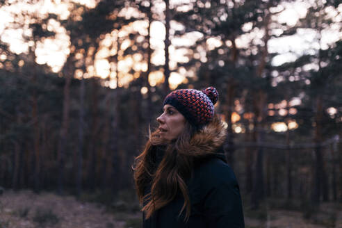 Frau mit Strickmütze im Wald bei Sonnenuntergang - MRRF01698