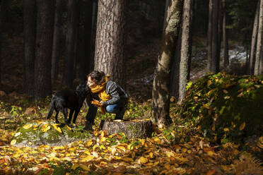 Frau in warmer Kleidung küsst Haustier im Herbst Wald - MRRF01716