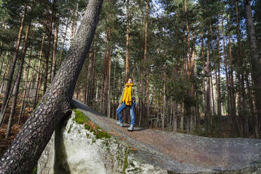 Woman standing on rock amidst trees in forest - MRRF01723