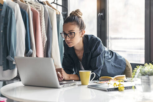 Businesswoman using laptop at desk in office - JSRF01703