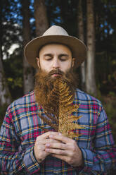 Bearded man with dry leaf at forest - AFVF09253