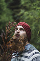 Thoughtful man with branch in woodland - AFVF09273