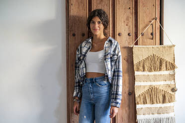 Girl with plaid shirt standing in front of wooden door - DLTSF02434