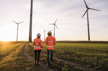 Ingenieure in reflektierender Kleidung beim Spaziergang im Windpark - UUF25091