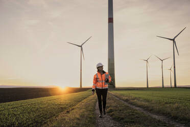 Ingenieur mit Tablet-PC auf dem Fußweg im Windpark - UUF25100