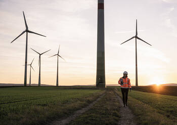 Ingenieur mit digitalem Tablet, der auf dem Fußweg eines Windparks wegschaut - UUF25101