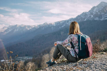 Tourist mit Rucksack auf Berg rastend - OMIF00175