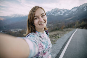 Smiling hiker taking selfie on mountain road - OMIF00180