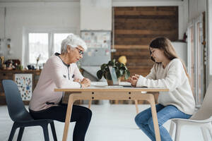 Enkelin und Großmutter sitzen am Tisch - JOSEF05930