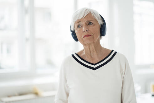Frau hört Musik über drahtlose Kopfhörer zu Hause - JOSEF05953