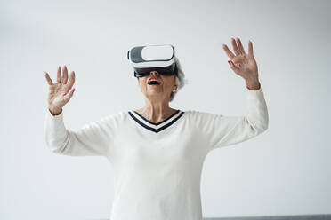 Woman using virtual reality headset in front of white wall - JOSEF05957