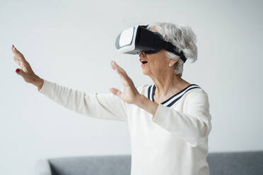 Senior woman using virtual reality simulator at home - JOSEF05959