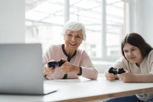 Ältere Frau spielt Videospiel mit Mädchen zu Hause - JOSEF05974