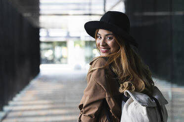 Woman with backpack looking over shoulder on footpath - PNAF02580