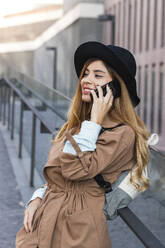Blond woman talking on mobile phone at railing - PNAF02583