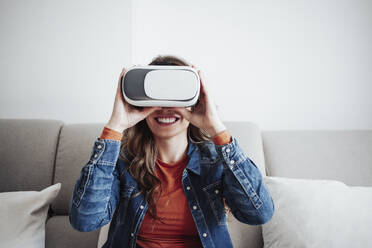 Smiling woman using virtual reality simulator at home - EBBF04896