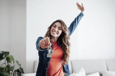 Happy woman holding house keys at home - EBBF04909