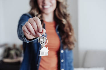 Junge Frau zeigt Hausschlüssel im neuen Haus - EBBF04925