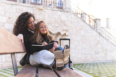 Mutter unterrichtet Tochter auf einer Bank in der Kathedrale von Burgos, Burgos, Spanien - JAQF00948