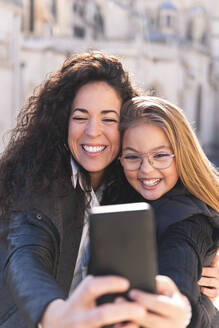 Glückliche Mutter und Tochter nehmen Selfie durch Handy - JAQF00958