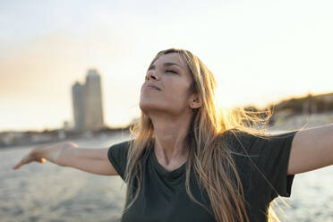 Woman with arms outstretched at Bogatell beach, Barcelona, Catalonia, Spain - JSRF01712