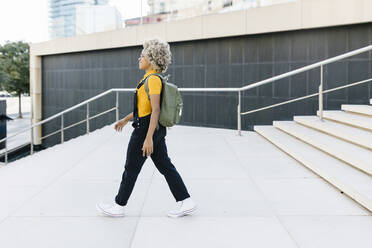 Frau mit Rucksack geht auf einer Treppe - XLGF02421