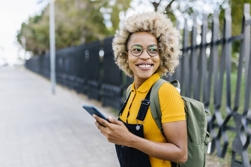 Woman with backpack and mobile phone on footpath - XLGF02453