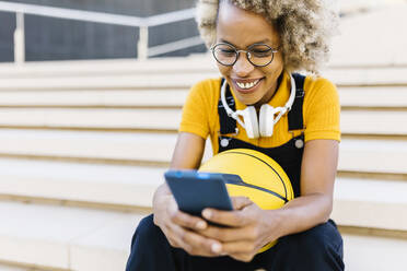 Lächelnde Frau mit Smartphone auf einer Treppe - XLGF02465