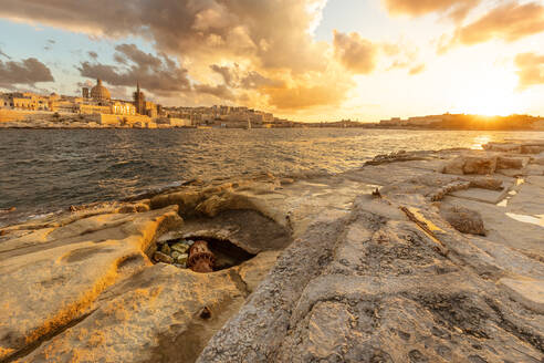 Malta, Sliema, Coastline of Tigne Point peninsula at moody sunset with town in background - FPF00242