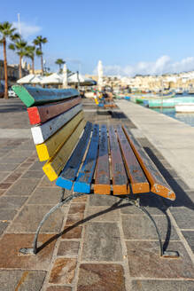 Empty multi colored bench overlooking city harbor - FPF00243