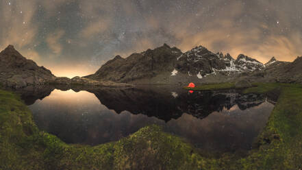 Scenic view of tent on lake shore against snowy mountain under cloudy milky way sky in evening located in Circo de Gredos cirque in Spain - ADSF31874