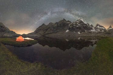 Scenic view of tent on lake shore against snowy mountain under cloudy milky way sky in evening located in Circo de Gredos cirque in Spain - ADSF31875