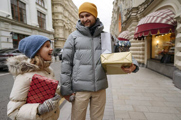 Father shopping Christmas gifts with daughter at city street - EYAF01813