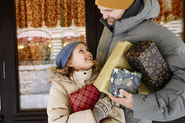 Vater und Tochter mit Weihnachtsgeschenken vor einem Geschäft - EYAF01815