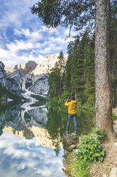 Wanderer Mann fotografiert Pragser Wildsee mit Smartphone bei Sonnenaufgang, Dolomiten, Südtirol, Italien, Europa - RHPLF20833
