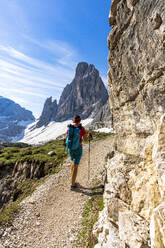 Rucksacktouristin mit Wanderstöcken genießt den Blick auf die Croda Dei Toni vom Weg aus, Sextner Dolomiten, Südtirol, Italien, Europa - RHPLF20839