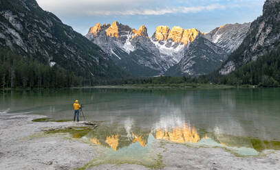 Fotograf mit Stativ bewundert die Dolomiten in der Morgendämmerung vom Landrosee aus, Dolomiten, Provinz Bozen, Südtirol, Italien, Europa - RHPLF20841