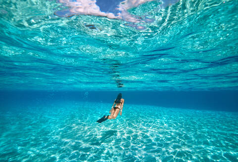 Eine junge Frau schwimmt unter Wasser in einer klaren, blauen, flachen Lagune mit sandigem Grund, Französisch-Polynesien, Südpazifische Inseln, Pazifik - RHPLF20878