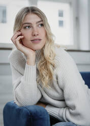 Beautiful young woman leaning on sofa at home - JBYF00034