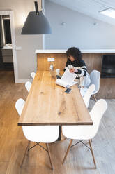 Junge Geschäftsfrau mit Notizblock arbeitet am Tisch im Büro - JAQF00985